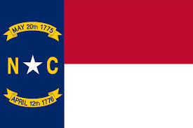 North Carolina state flag with N, C, star, and 2 dates on ribbons on vertical blue stripe left of red and white stripes.