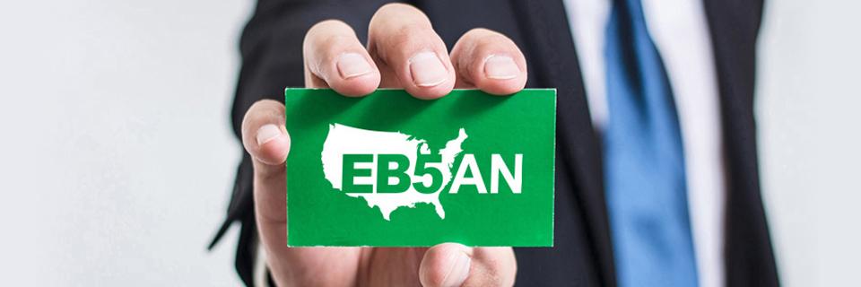 A hand holding a green card with the EB5AN logo on it.
