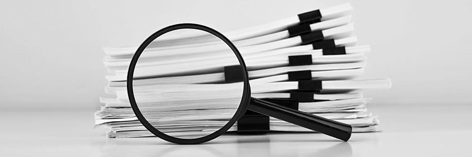 An experienced immigration lawyer carefully reviews an USCIS RFE on behalf of his client. He is using a magnifying glass to help him read the details.