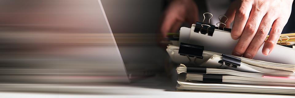 A close-up of a hand holding documents for Form I-485 processing.