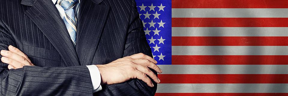 A person standing in front of the American flag. An employee in a suit who wants to obtain permanent residence (green card).