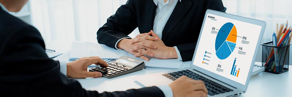 A financial advisor working on some business graphs on a computer and a calculator.