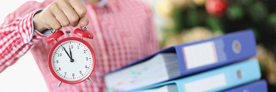 A close-up of a person holding a clock and some document folders, symbolizing immigration delays.