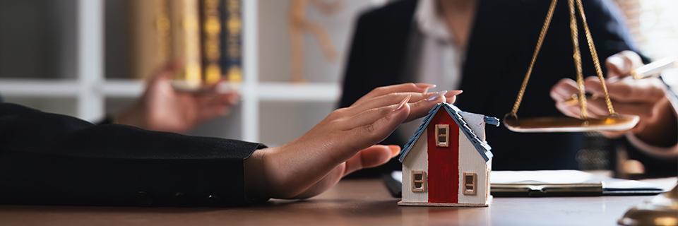 A project developers hand touching a small model house, symbolizing investment in a job creating entity.