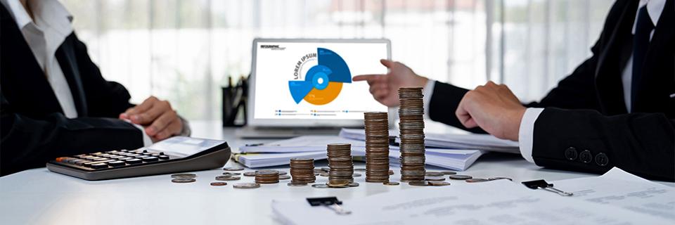 An immigration professional pointing at a graph of investment funds on the computer, with a calculator and a stack of coins on the desk.