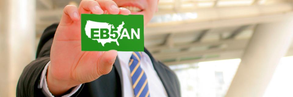 An EB-5 process expert holding up a green card with the EB5AN logo on it.