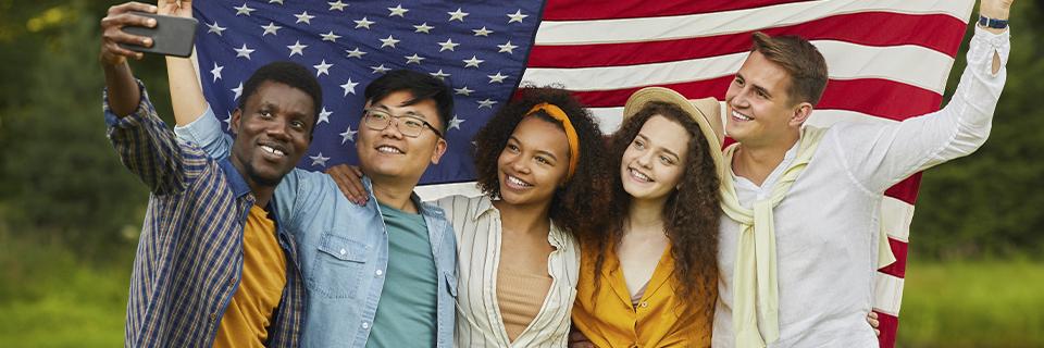 A group of young EB-5 dependents taking a picture with the American flag.