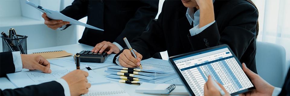 A close-up of people writing on some documents, making calculations for EB-5 financing options. 