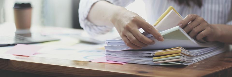 A person holding a stack of EB-5 visa supporting documents on a desk.