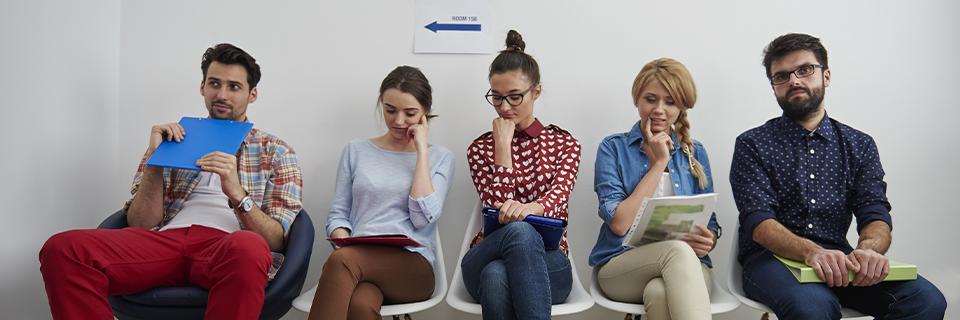 A group of people sitting in chairs, waiting for processing.