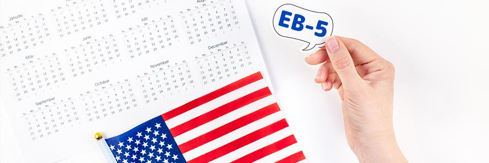 A calendar and an American flag next to a hand holding up the word EB-5.