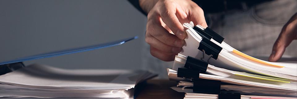 The hands of a principal applicant piling up supporting documents.
