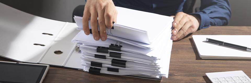 An immigration lawyer holding a stack of documents on a desk.