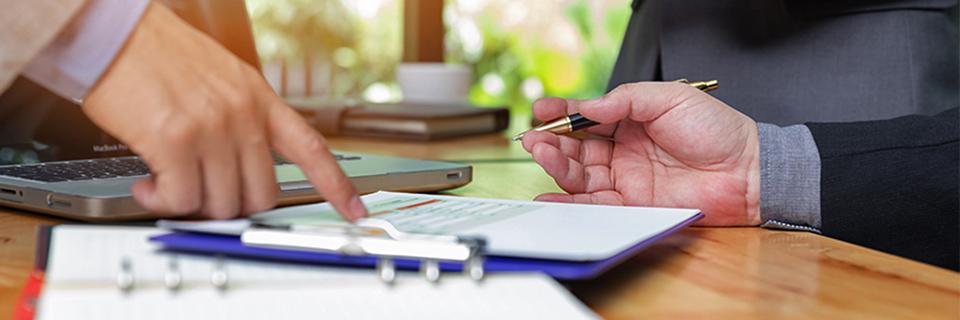 An EB-5 expert pointing at an investor's adjustment of status application on a desk.