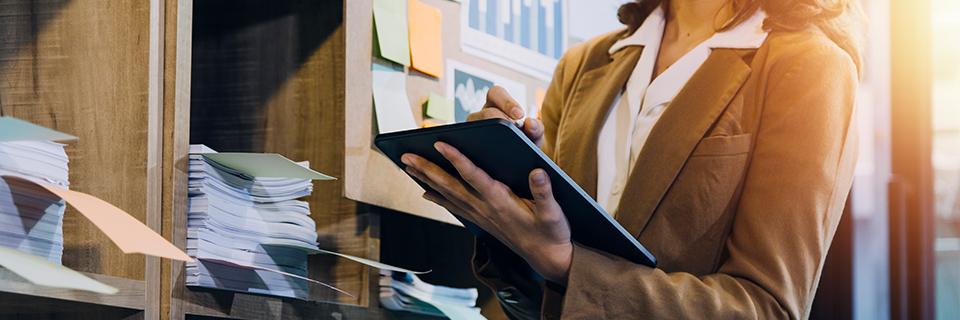 An immigration lawyer working on an online green card application on a tablet in front of a stack of supporting documents.