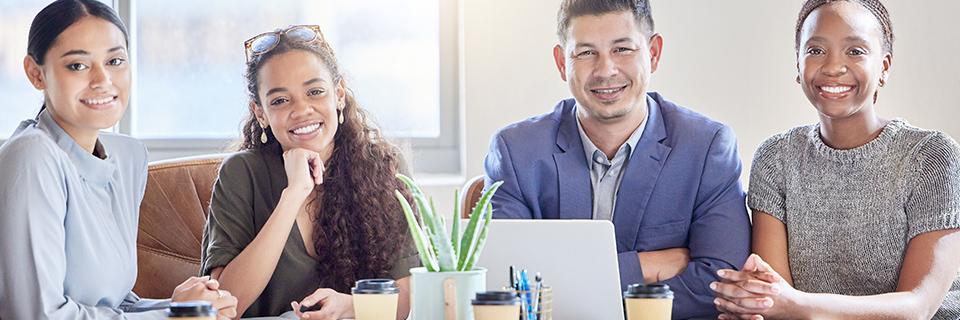 A group of business people sitting at a table, smiling at the camera.