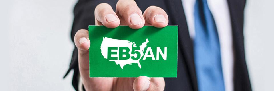 A hand holding a green card with the EB5AN logo on it.