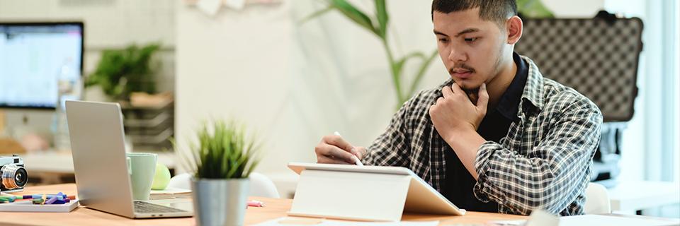 A person sitting at a table checking a tablet.