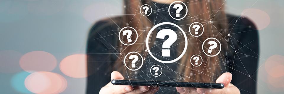 A person holding a phone with question mark icons hovering above it.