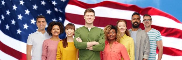 A group of people posing for a photo and smiling in front of a large American flag.