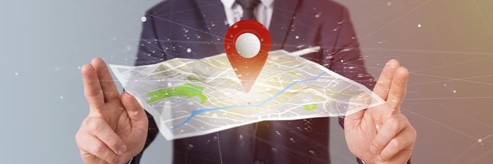 A person holding a map with a digital pin dropped in the middle of it, symbolizing targeted employment area locations for EB5 investments.