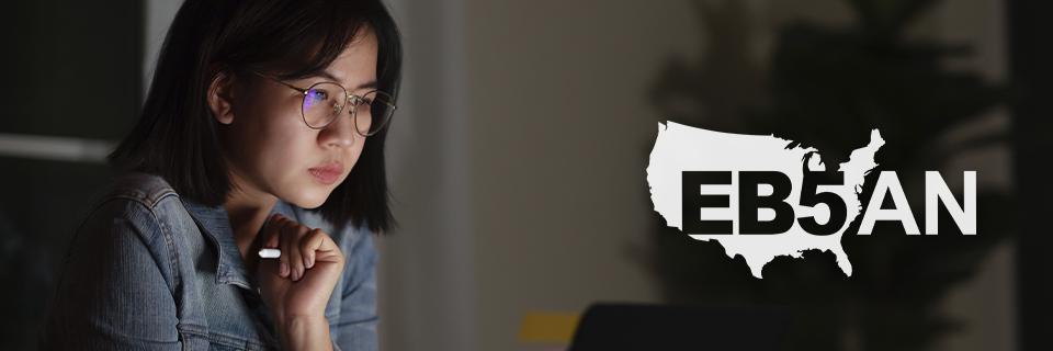 An Asian EB5 investor looking at a computer screen next to the EB5AN logo.
