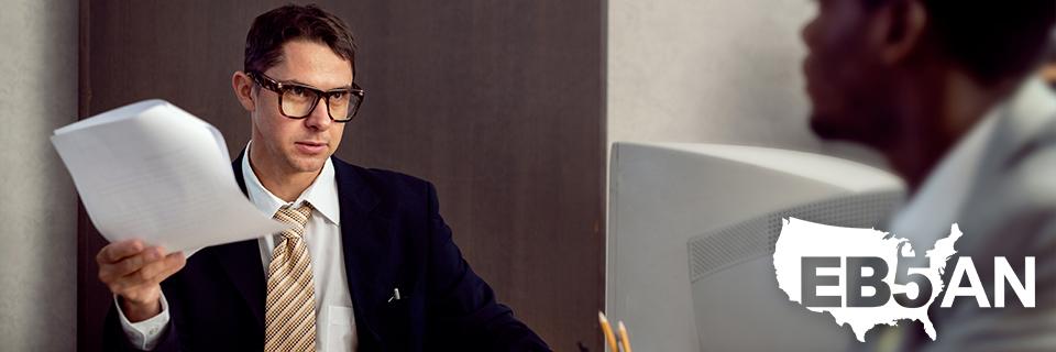 An EB5 expert or immigration attorney talking to a client with documents in his hand, next to the EB5AN logo.