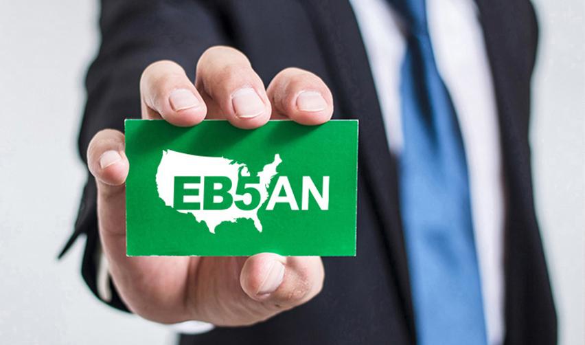 A hand holding a green card with the EB5AN logo on it.