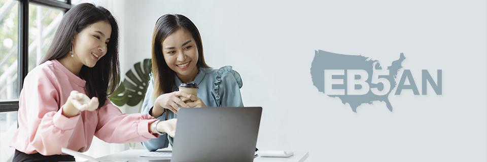 Two alien entrepreneurs looking at a computer at a regional center meeting or video call, next to the EB5AN logo.