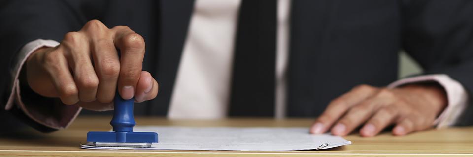 A United States Citizenship and Immigration Services officer stamping a visa application document.