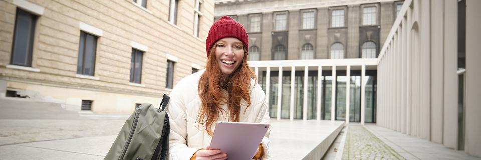 An EB5 investor's child smiling at the camera on a U.S. college campus.