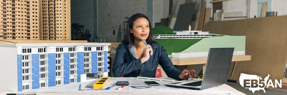 A foreign investor surrounding by model real estate projects trying to decide on her options, with the EB5AN logo on the corner.