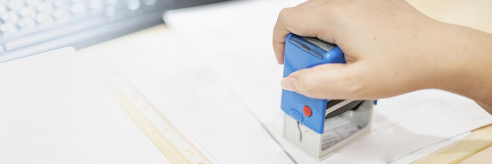 A government official stamping some visa documents, implying how EB5AN can help EB5 investors through a successful EB5 process.