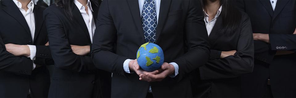 An EB5 investor holding a globe in his hand with a group of industry professionals by his side.
