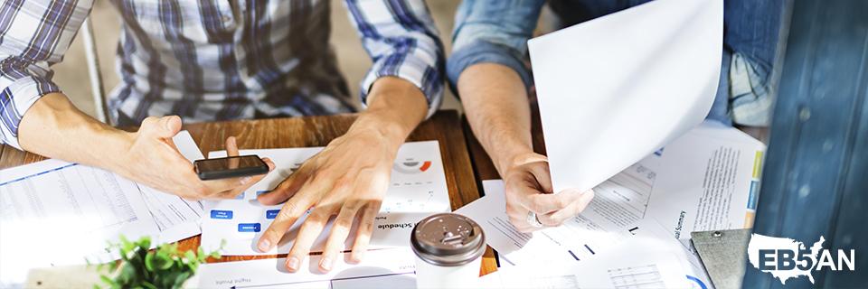 A group of Eb5 investors going over some regional center project documents and doing their due diligence with the EB5AN logo on the corner.