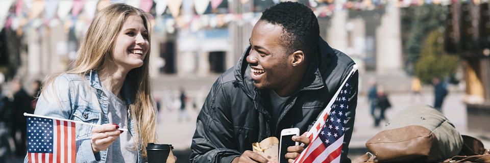 Two Eb5 investors celebrating their US citizenship with American flags in their hands.