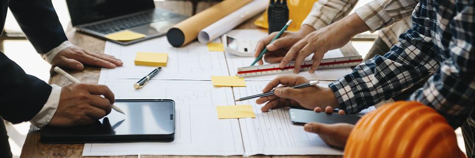 Construction planning team discussing blueprints and job creation strategies for an EB5 project, emphasizing real estate development under regional centers.