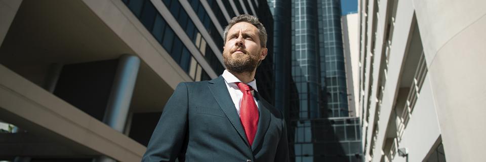 Ambitious businessman in a suit standing in front of modern skyscrapers, illustrating career and financial growth through the EB5 visa program.