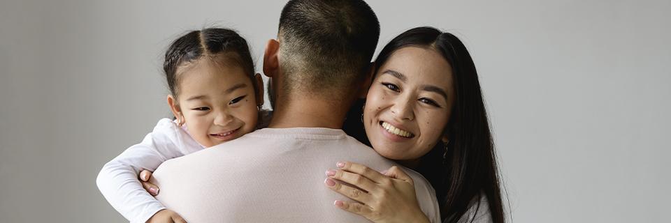 A happy Asian family embraces. The image represents the family reunification benefits of U.S. Green Card sponsorship.