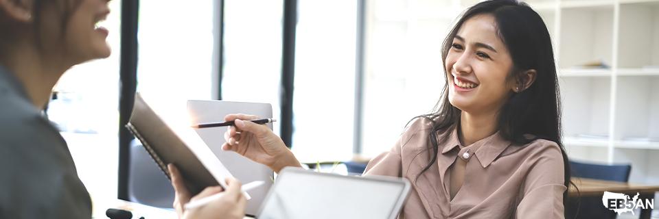 Smiling professionals discussing documents in a an office, symbolizing expert consultation and personalized EB5 immigration guidance by EB5AN.