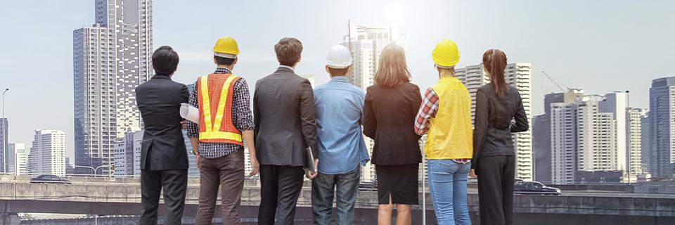 A group facing city skyline with construction gear, symbolizing EB5 investors and developers evaluating rural and urban projects for set-aside visa categories.