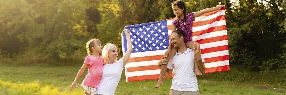 Happy family holding an American flag, illustrating the family inclusion benefits of the EB5 visa for entrepreneurs.