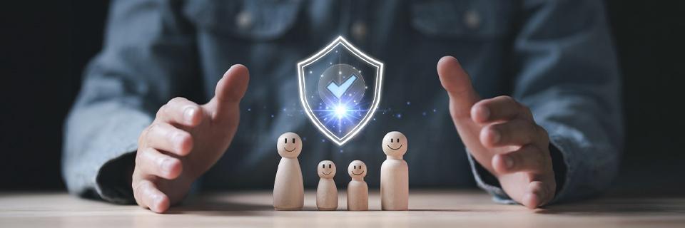 Hands shielding smiling wooden family figures under a glowing shield icon, symbolizing protection, stability, and future planning for EB5 investor families.