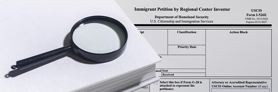 A magnifying glass on immigration paperwork and Form I-526E, symbolizing USCIS scrutiny of EB5 source of funds.