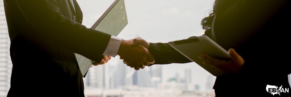Business professionals shaking hands above the EB5AN logo, highlighting the role of advisors and legal teams in the EB5 source of funds process.
