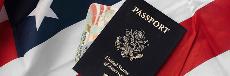 A U.S. passport and Green Card resting on the American flag, representing successful transition from OPT status to lawful permanent residency through the EB5 program with the help of EB5AN.