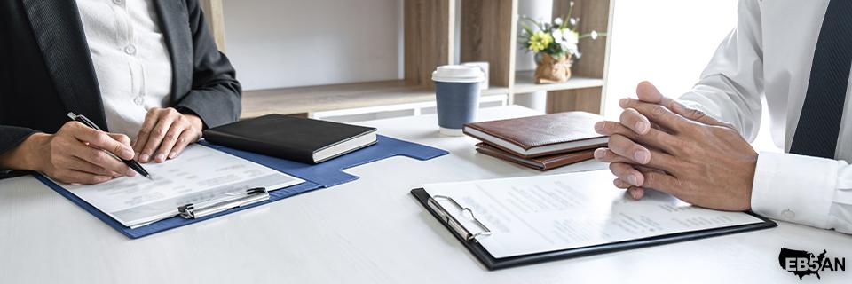 The EB5AN logo next to two professionals who discuss EB5 investment timelines across a desk, highlighting due diligence and advisory support for Green Card success.