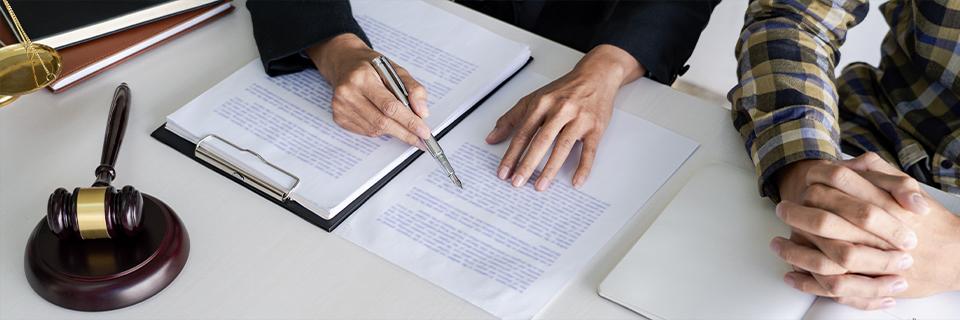 A legal advisor pointing to paperwork while sitting across from a client, with a gavel nearby—illustrating professional legal help after an EB5 petition denial.