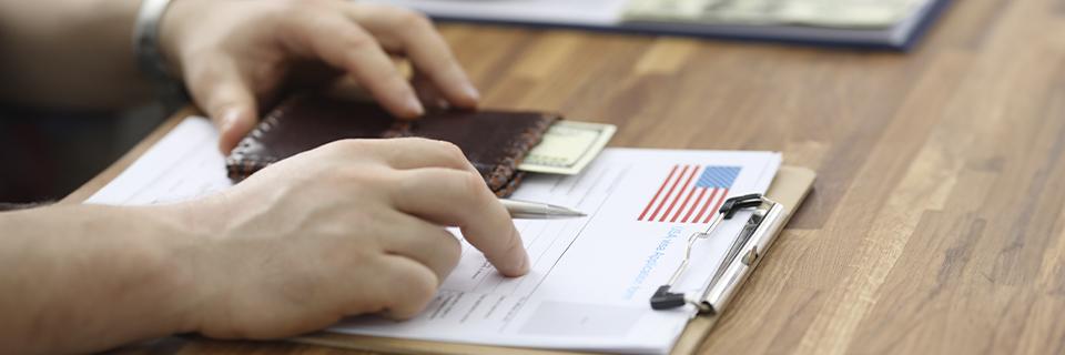 Close-up of an investor’s hands reviewing a U.S. immigration form on a clipboard, representing the EB5 visa application process for set-aside categories.