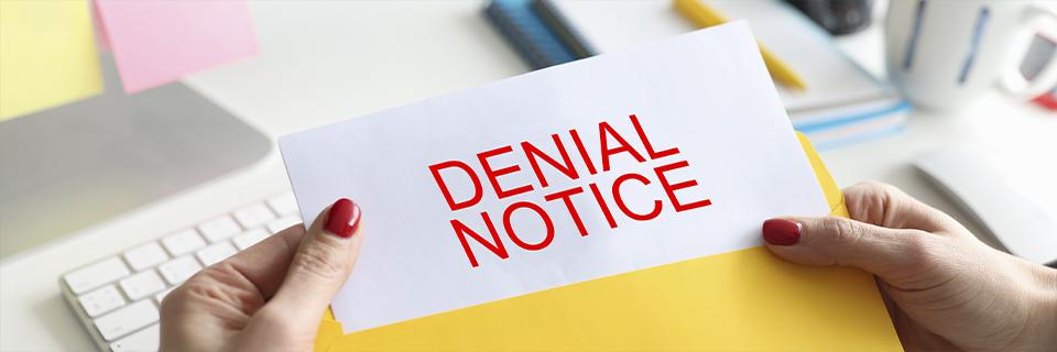 Hands holding an envelope labeled “DENIAL NOTICE” in bold red letters—representing an EB5 applicant receiving a rejection letter from USCIS.